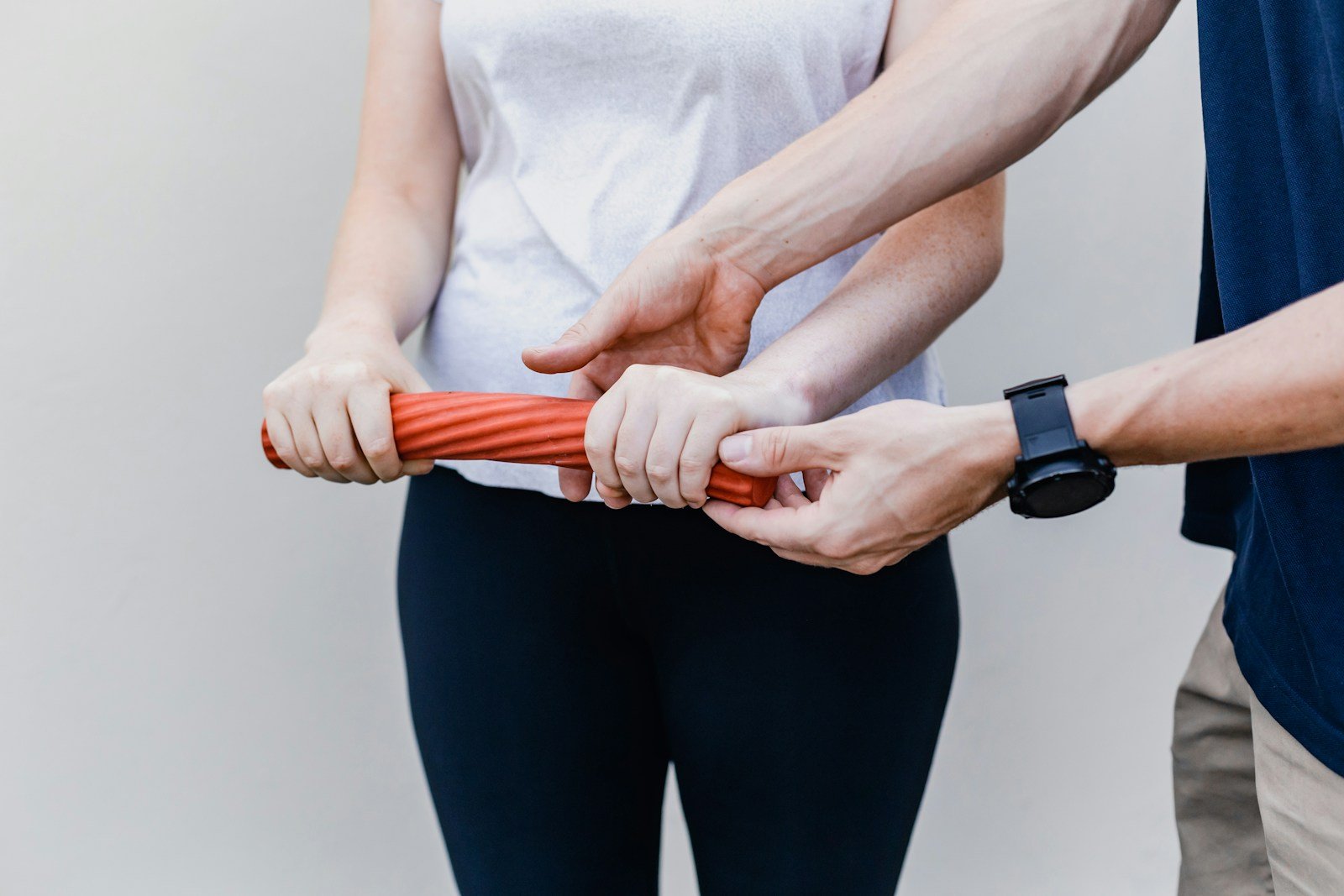 5 Effective Rehab Equipment for Muscle Recovery 1 Man and woman holding an orange rehab equipment tool for muscle recovery and rehabilitation exercises.