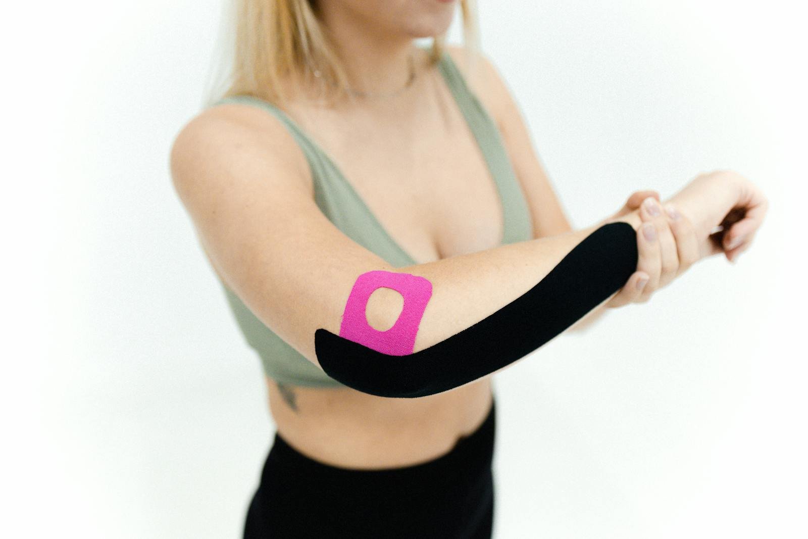 Best Injury Prevention Gear for Athletes: Top Picks for 2025 1 Injury prevention : Close-up of a woman applying kinesio tape on her arm for therapeutic treatment on a white background.
